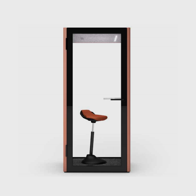 A minimalist privacy booth with a dark frame and large clear glass front, revealing its interior. Inside the booth, there's a simple high-standing desk and a modern burnt-orange stool. The booth is designed for quick, individual tasks or short breaks in a contemporary workspace.